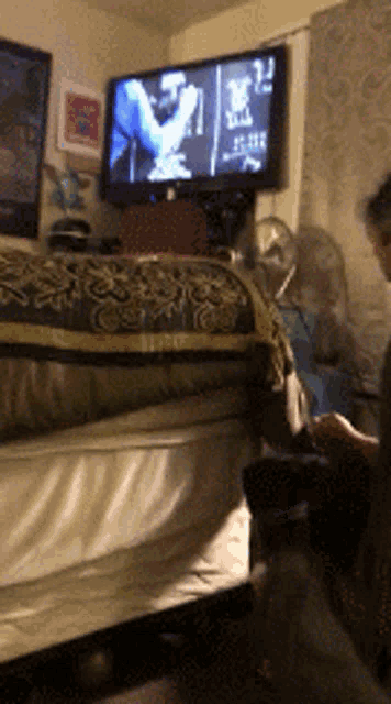 a man is sitting in front of a flat screen tv that shows a man playing a guitar