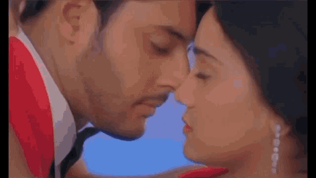 a man and a woman are kissing each other in a close up of their faces .