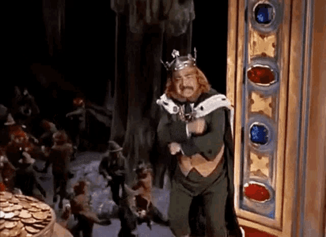 a man in a king 's costume is standing in front of a crowd of people .