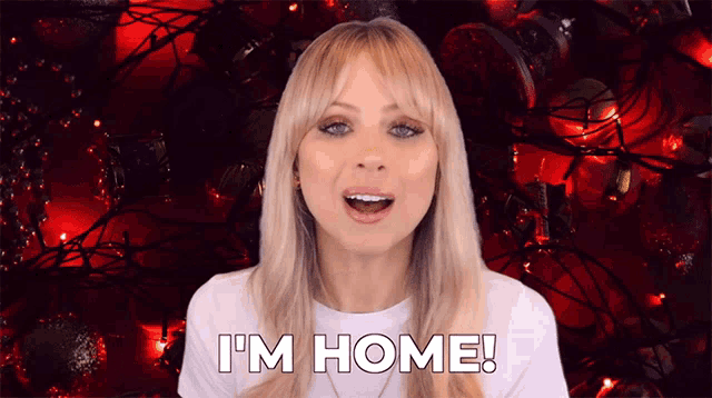 a woman says " i 'm home " in front of christmas lights