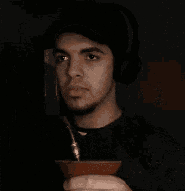 a man wearing headphones is drinking from a clay cup