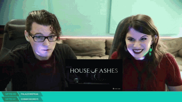 a man and a woman are looking at a screen that says house of ashes on it