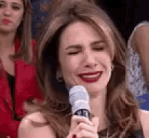 a woman is crying while holding a microphone with her eyes closed .