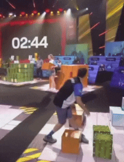 a man stands in front of a stage with the time of 12:44