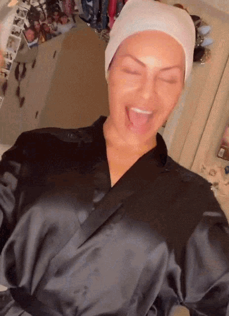 a woman wearing a black robe and a white headband with her tongue out