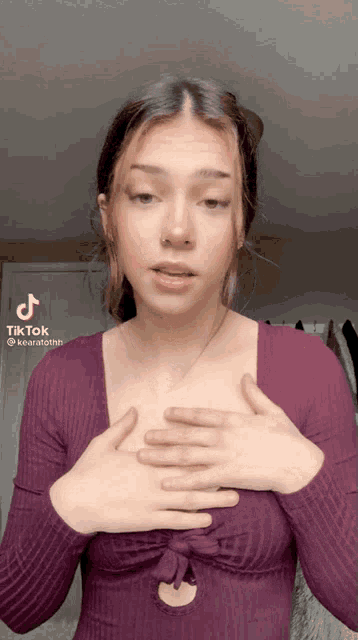a woman in a purple shirt is making a tik tok video