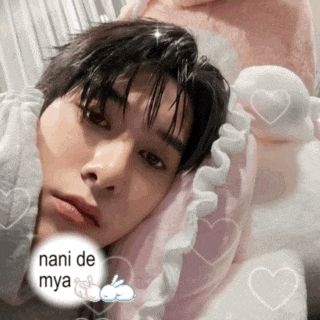 a young man is laying on a pink pillow with hearts around him and the words nani de mya