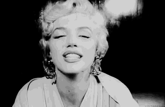 a black and white photo of marilyn monroe smiling with her eyes closed in a black and white photo .