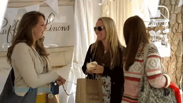 three women standing in front of a sign that says caramel colors