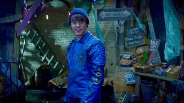 a young man in a blue jacket stands in front of a no way sign