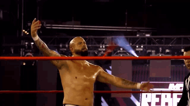 a shirtless wrestler stands in a ring with his arms outstretched in front of a sign that says ffaf