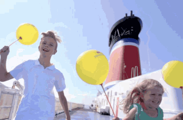 a boy and a girl are holding yellow balloons in front of a red and white ship that says maxi