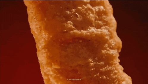 a close up of a fried chicken nugget on a red surface