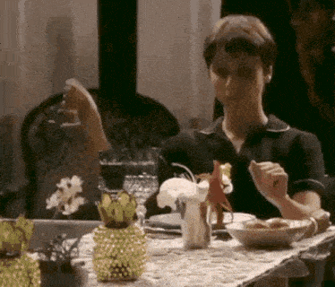 a woman is sitting at a table with a glass of wine in her hand