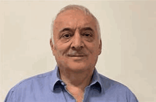 a man wearing a blue shirt is smiling for the camera .