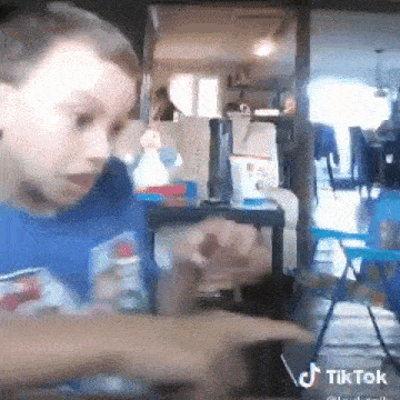 a young boy is sitting at a table in a living room playing with a toy .