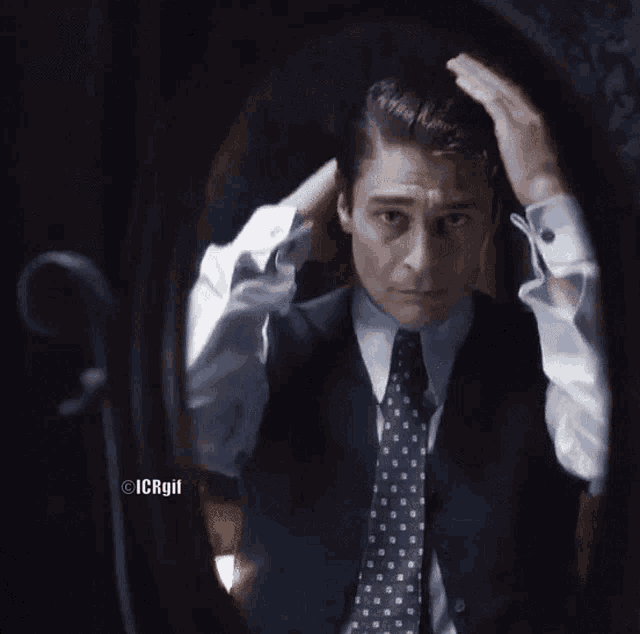 a man in a suit and tie looking at himself in a mirror