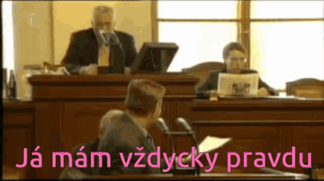 a man in a suit stands at a podium with the words ja mam vzdycky pravdu written in pink