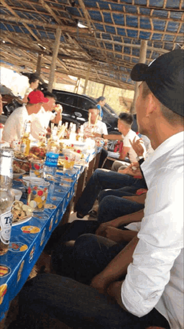 a group of people sit at a long table with a bottle of tiger beer on it