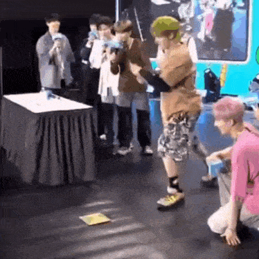 a group of people are playing a game on a stage while a man is kneeling on the floor .