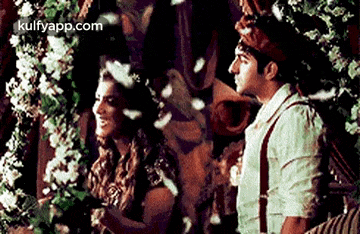 a man and a woman are standing next to each other in front of a flower wall .