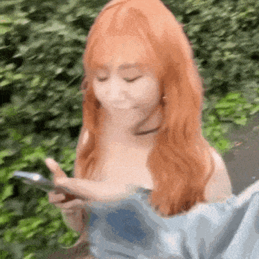a woman with long red hair is looking at her phone .