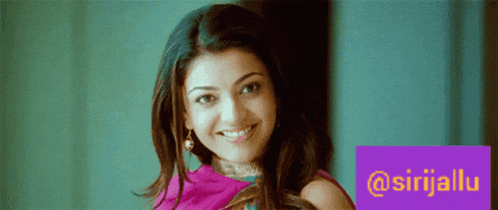 a woman is smiling in front of a purple sign that says @sirijallu