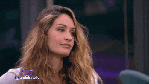 a close up of a woman 's face with #grandefratello written in blue
