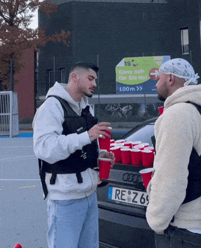 two men standing in front of an audi with a license plate that says re z 69