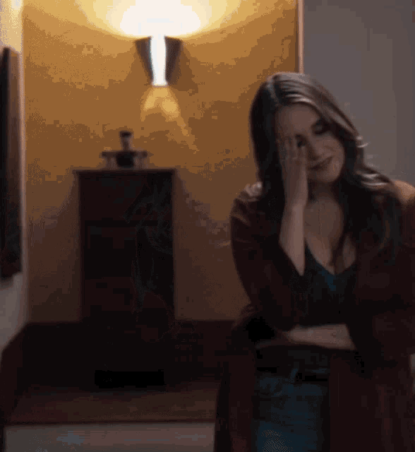 a woman covering her face with her hand while standing in a hallway