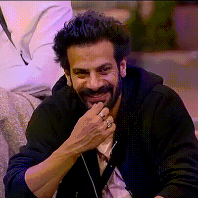 a man with a beard and a ring on his finger smiles