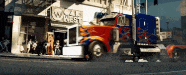 a truck is driving down a street in front of a building that says cal west