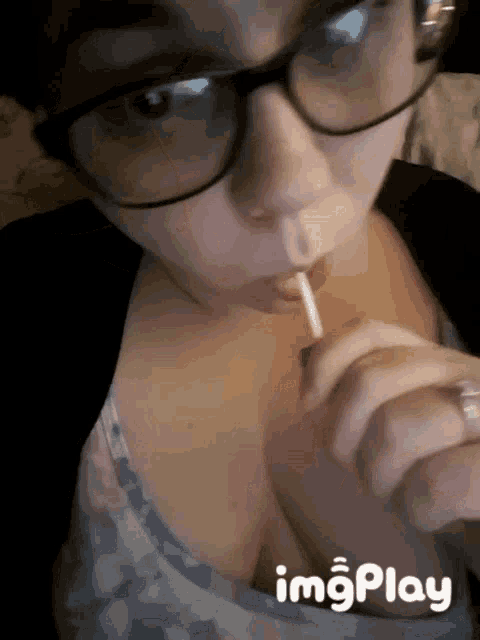 a woman with glasses is licking a lollipop with imgplay written on the bottom