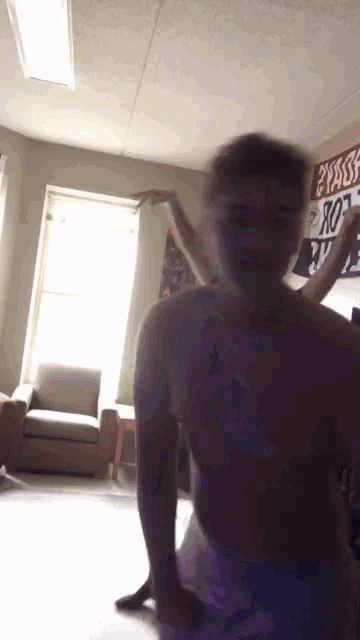 a man without a shirt is dancing in a room with a sign on the wall that says no