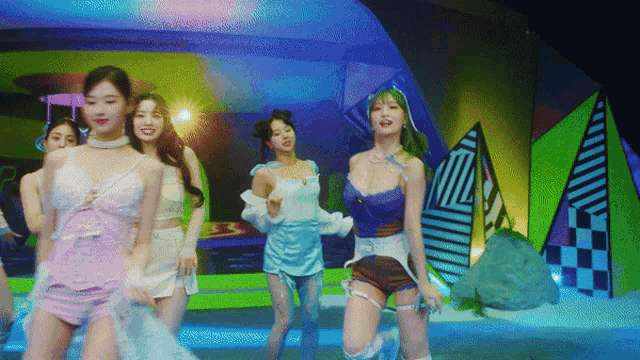 a group of women are dancing on a stage in front of a colorful backdrop