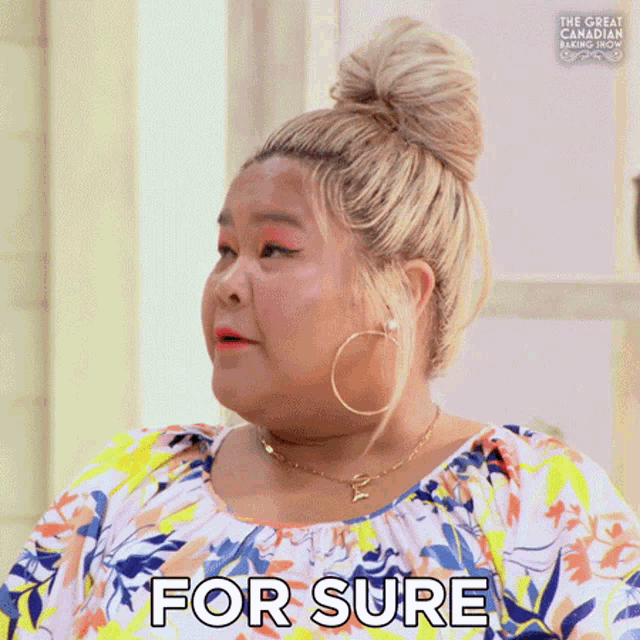 a woman with blonde hair and hoop earrings is wearing a floral dress and says `` for sure '' .