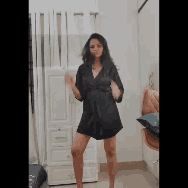 a woman in a black dress is dancing in a room