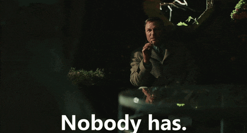 a man sitting at a table with the words " nobody has " behind him