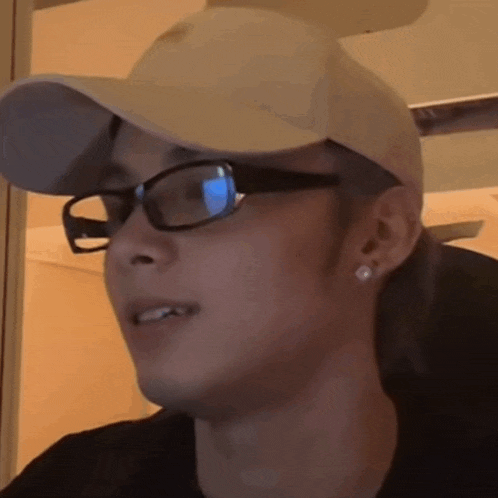 a close up of a person wearing glasses and a baseball cap