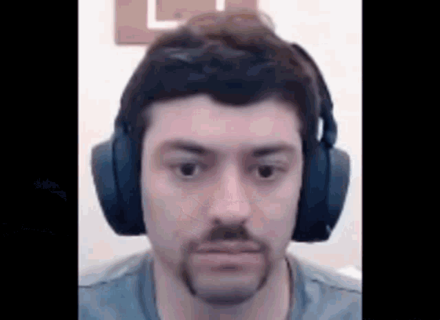 a man with a beard wearing headphones is looking at the camera .