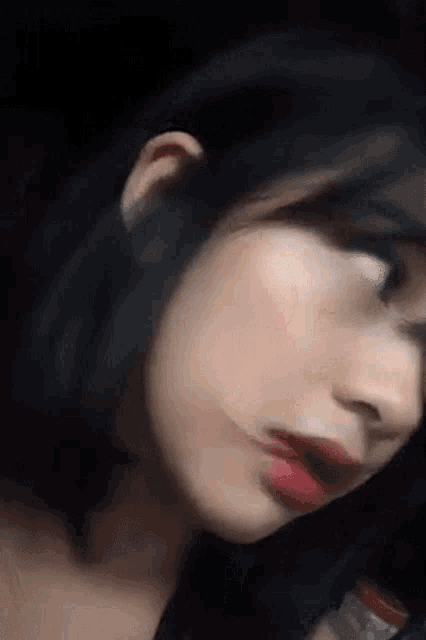 a close up of a woman 's face with red lips and black hair .