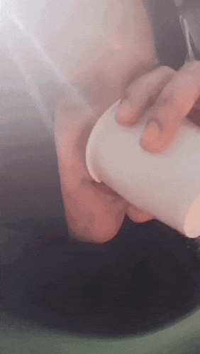 a person is holding a white cup in their hands