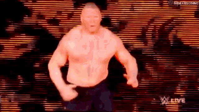 a man without a shirt is standing in front of a large screen .
