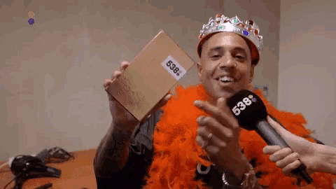 a man wearing a crown is holding a box with the number 538 written on it