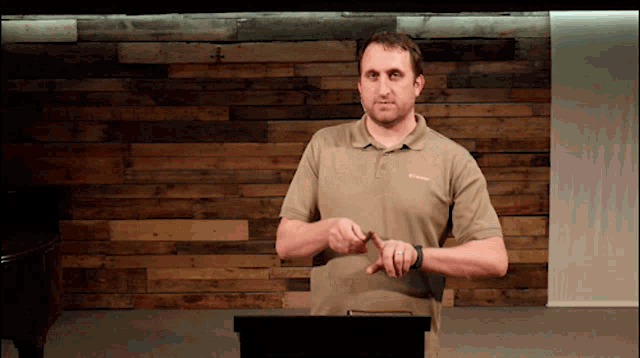 a man wearing a columbia shirt stands in front of a wood wall