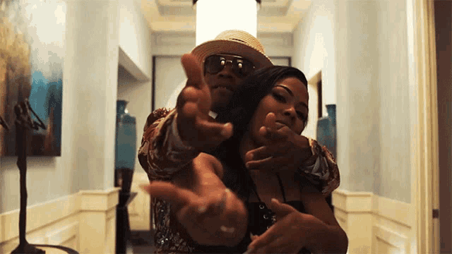 a man in a straw hat is pointing at a woman