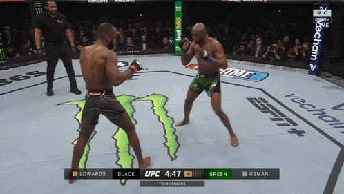 two men are fighting in a boxing ring with a monster logo on the floor
