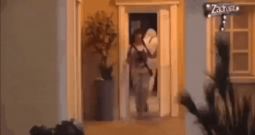 a woman is walking through a doorway in a house holding a bag .