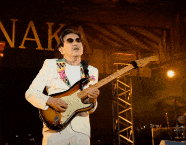 a man playing a guitar in front of a sign that says nak