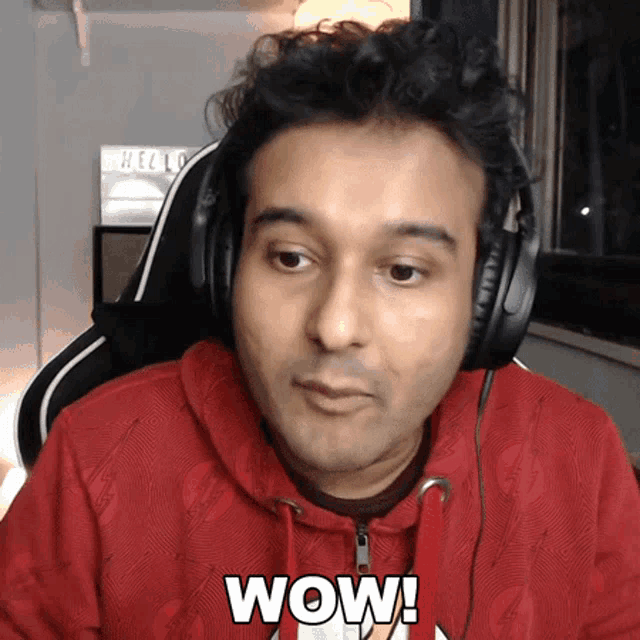 a man wearing headphones and a red hoodie has the word wow on his chest